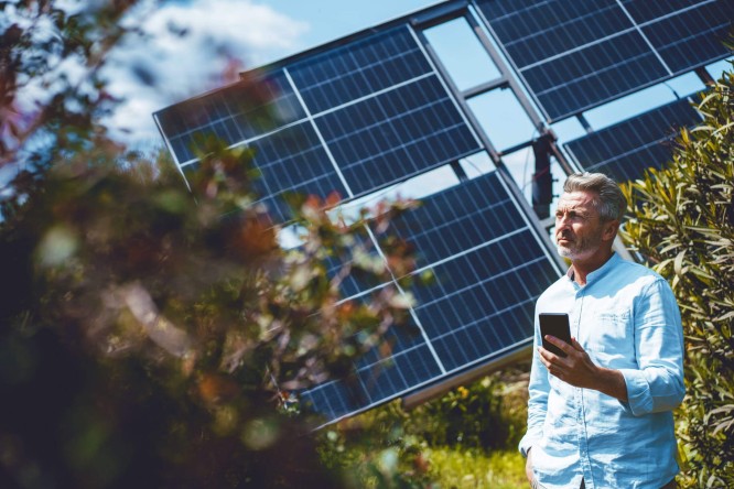 Ein Mann steht vor Solarpanelen und betrachtet die nachhaltige Energiequelle.