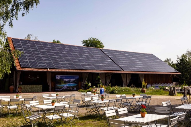 Gaststätte mit Solarpanels auf dem Dach und leeren Tischen und Stühlen im Außenbereich