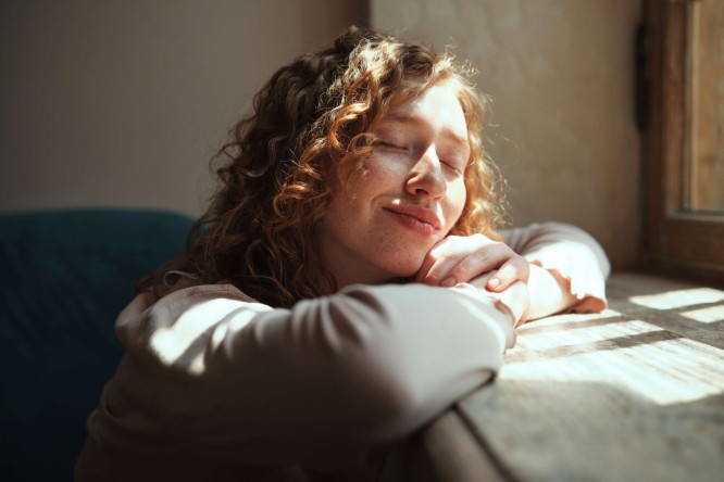 Eine Frau lehnt sich entspannt zurück und genießt die Sonnenstrahlen. Symbol für Entspannung und nachhaltige Energie. Stromeinspeisevergütung Auri Sun.