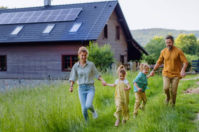 Eine Familie genießt die Natur vor ihrem Haus mit Solaranlage. Nachhaltiges Leben mit erneuerbarer Energie im Eigenheim. Energiegemeinschaft Auri Connect